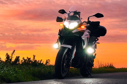 moto sur le bord d'une route avec top case noga aluminium et feux addtionnels noga evo le fond est un couché de soleil